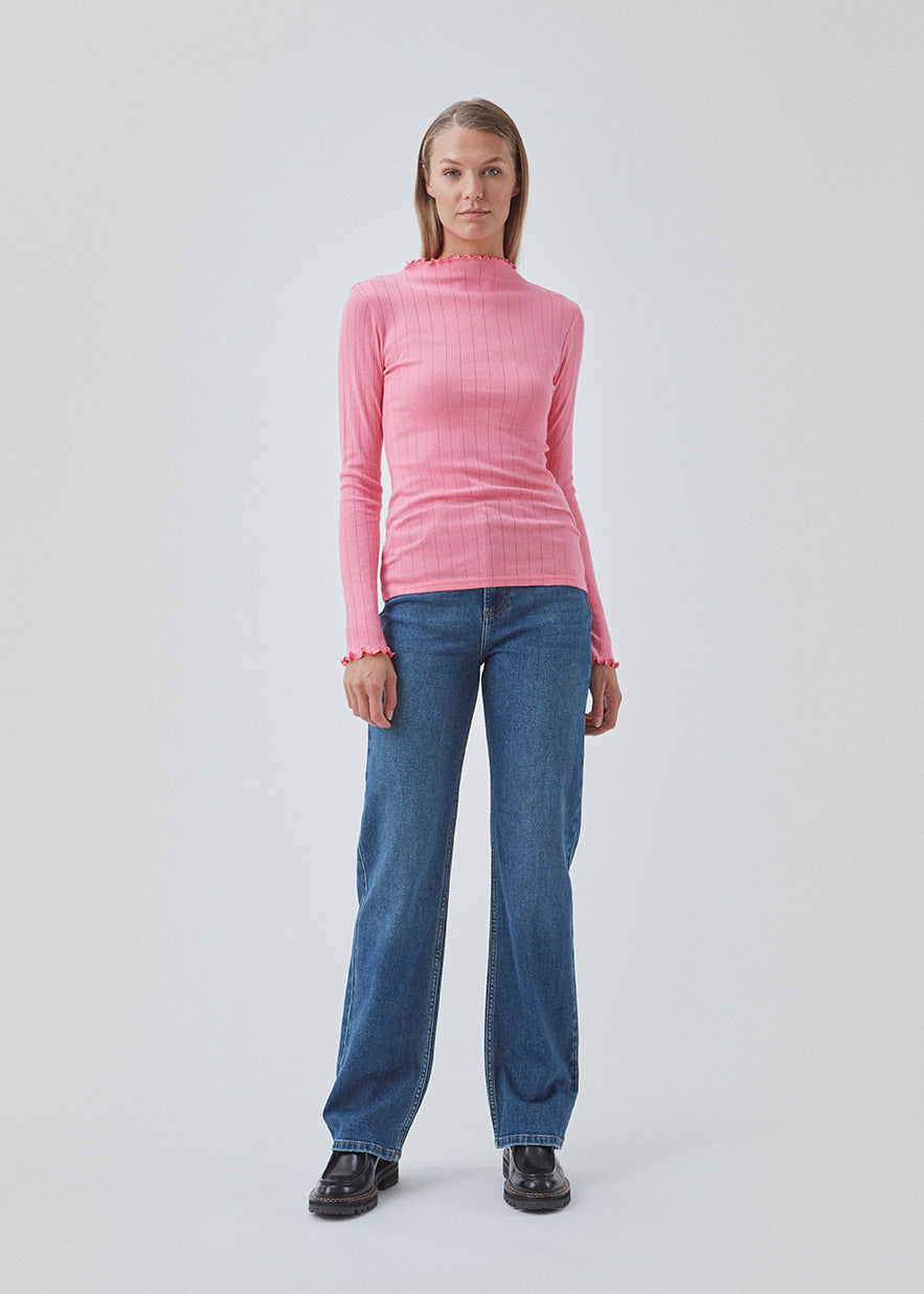 Tight fitted t-shirt in pink with a medium high neck. Issy t-neck has feminine lettuce hem on neck and sleeves. The quality is a soft jersey with a feminine pointelle pattern.