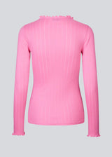 Tight fitted t-shirt in pink with a medium high neck. Issy t-neck has feminine lettuce hem on neck and sleeves. The quality is a soft jersey with a feminine pointelle pattern.