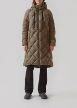 Smart down coat in a diamond quilt in dark green. The coat has a hood with adjustable strings and two zipped pockets. Kyra coat has a down filling, which gives an outstanding insulation from the cold - even on the coldest days. Keep you warm down to -15 degrees. It’s water repellant, wind resistant