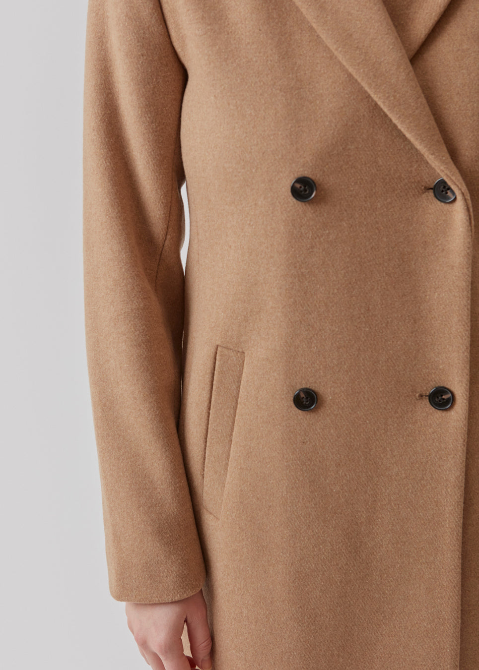 Beautiful, knee-length wool coat in light brown. Odelia coat is closed at front by 4 buttons and is fitted around the waist, which gives a feminine look. Because of the high content of wool the jacket will be perfect for fall and the mild winters.