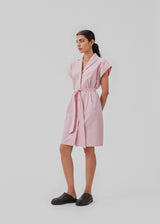 Panne dress is a cotton dress in the color dusty sorbet with a beautiful silhouette. The dress features a nice collar, tie band, and a sleeveless design with wide shoulders. The model is 173 cm and wears a size S/36.