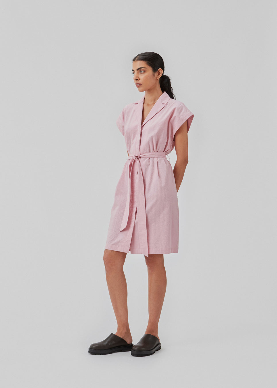 Panne dress is a cotton dress in the color dusty sorbet with a beautiful silhouette. The dress features a nice collar, tie band, and a sleeveless design with wide shoulders. The model is 173 cm and wears a size S/36.