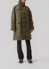 Quilted jacket with down filling i green. ScarlettMD jacket is knee length with a high stand-up collar and a zipper with wind flap with press-studs. The jacket has two patch pockets with press studs in front and an elasticated cuff. The model is 177 cm and wears a size S/36.
