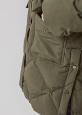 Quilted jacket with down filling i green. ScarlettMD jacket is knee length with a high stand-up collar and a zipper with wind flap with press-studs. The jacket has two patch pockets with press studs in front and an elasticated cuff. The model is 177 cm and wears a size S/36.