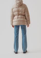 Puffer jacket in beige with an oversized silhouette and adjustable drawstring waist. StellaMD jacket is designed with a high-standing collar, hood, two-way zipper and paspel pockets.