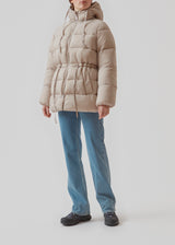 Puffer jacket in beige with an oversized silhouette and adjustable drawstring waist. StellaMD jacket is designed with a high-standing collar, hood, two-way zipper and paspel pockets.