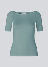 Tansy top in the color stormy sea has a simple look with a wide neckline at front and back and narrow sleeves. The top is slim fit without being tight. The model is 174 cm and wears a size S/36