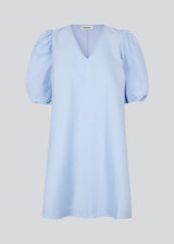 Short dress in a structured and shiny quality in blue. TelmaMD dress has a relaxed fit with a v-shaped neckline and short puff sleeves.
