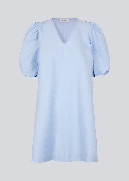 Short dress in a structured and shiny quality in blue. TelmaMD dress has a relaxed fit with a v-shaped neckline and short puff sleeves.