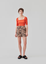 Tight fit top in red in a ribbed cotton jersey with a deep neckline in front and short sleeves cutting just above the elbow. The model is 175 cm and wears a size S/36.