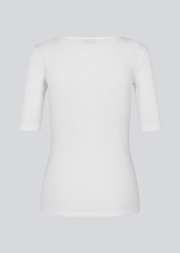 Tight fit top in white in a ribbed cotton jersey with a deep neckline in front and short sleeves cutting just above the elbow. 