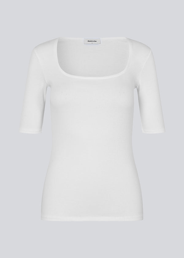 Tight fit top in white in a ribbed cotton jersey with a deep neckline in front and short sleeves cutting just above the elbow. 