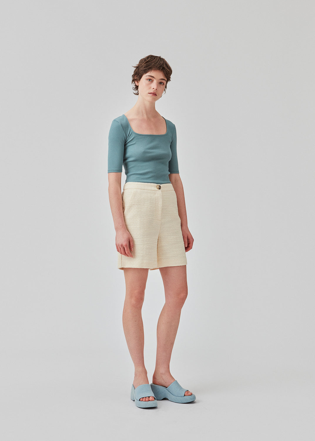 Tight fit top in blue in a ribbed cotton jersey with a deep neckline in front and short sleeves cutting just above the elbow.