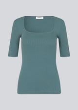 Tight fit top in blue in a ribbed cotton jersey with a deep neckline in front and short sleeves cutting just above the elbow.