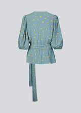 Floral top with a tie at the waist in blue with print. TuckerMD print top is a wrap shirt with short loose sleeves. The shirt is made of 100% responsible material.
