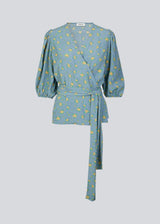 Floral top with a tie at the waist in blue with print. TuckerMD print top is a wrap shirt with short loose sleeves. The shirt is made of 100% responsible material.