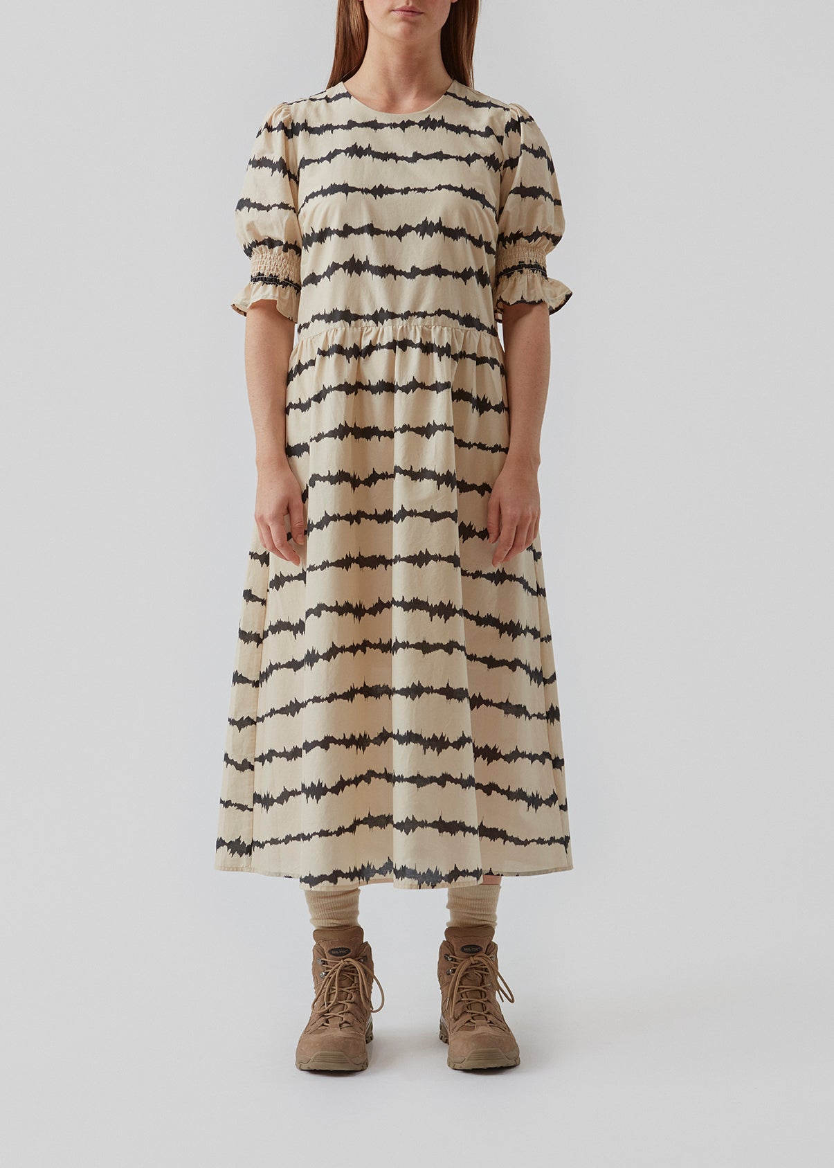 Midi kjole med korte pufærmer med elastik. Poem print dress har et batikfarvet print og er lavet i ansvarligt bomuld. Skørtet tilføjer masser af volumen og et feminint udtryk. Modellen er 173 cm og har en størrelse S/36 på
