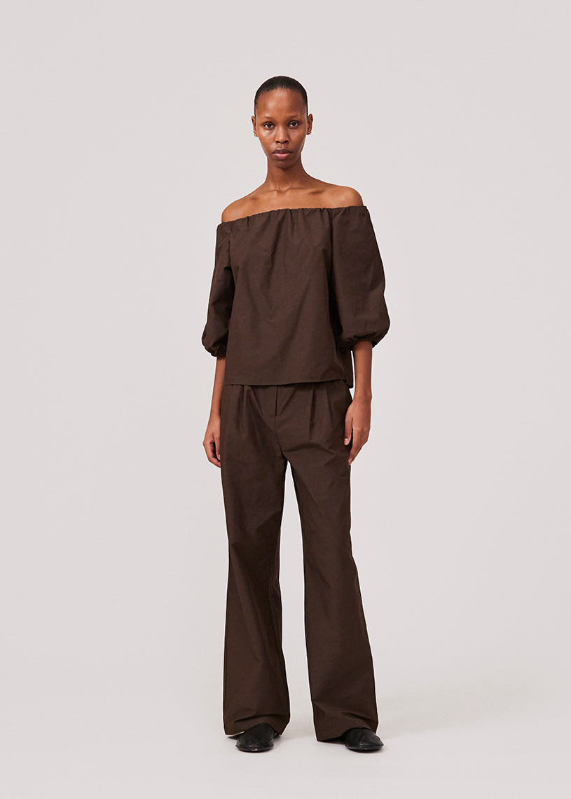 Suit pants in dark brown in a cotton blend with a relaxed silhouette and wide legs. DeenMD pants have a medium waist, zip fly, and pleats at the front. The model is 177 cm and wears a size S/36.