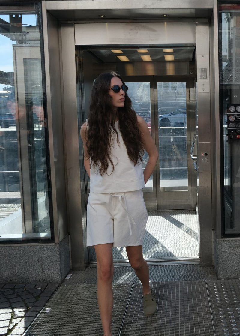 White denim shorts with wide legs in cotton denim. Naomamd solid shorts have a high waist, front and back pockets, and a tie band at the waist.