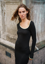 Tight-fitted maxi dress in stretchy rib. FaizMD dress has long sleeves with slit, slits at the sides of the skirt and an asymmetrical neckline with contrasting bias tape. The model is 175 cm and wears a size S/36.