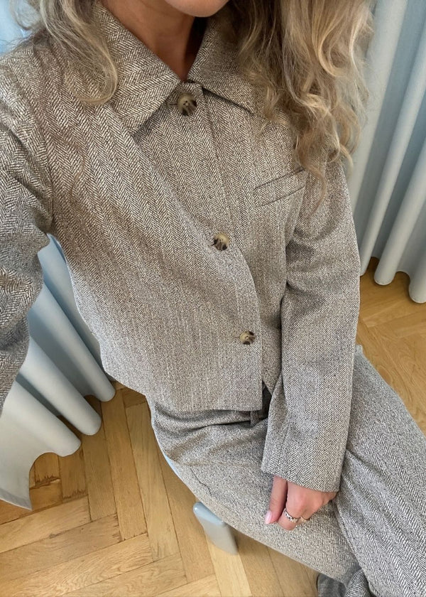 Short jacket with a shirt collar and front button closure. Popemd jacket has long sleeves with slits and a chest pocket. The model is 175 cm and wears a size S/36.