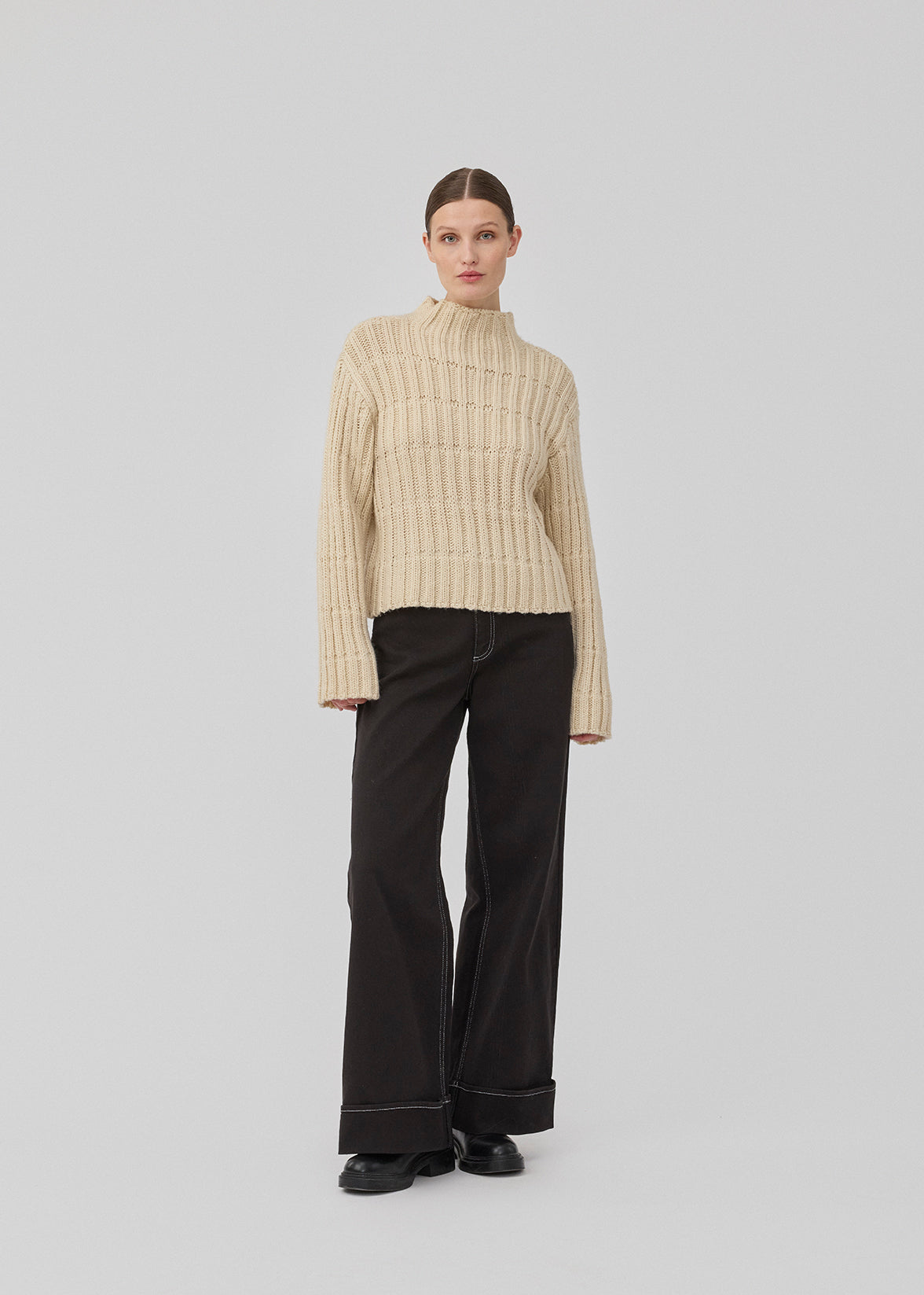 Striktrøje i off white med lav skuldersøm og lange brede ærmer. FelipeMD t-neck har en høj hals med ribkanter ved hals og forneden på ærmerne.