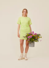 Fitted mini dress in green with an elastic gathering on the side. IbiMD dress has an invisible zipper in the back.