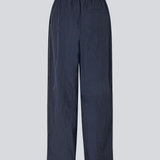 Dark blue tracksuitpants in 100% recycled nylon. Volmermd pants has piping along the sideseam and cutline details for a sporty look.