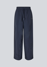 Dark blue tracksuitpants in 100% recycled nylon. Volmermd pants has piping along the sideseam and cutline details for a sporty look.