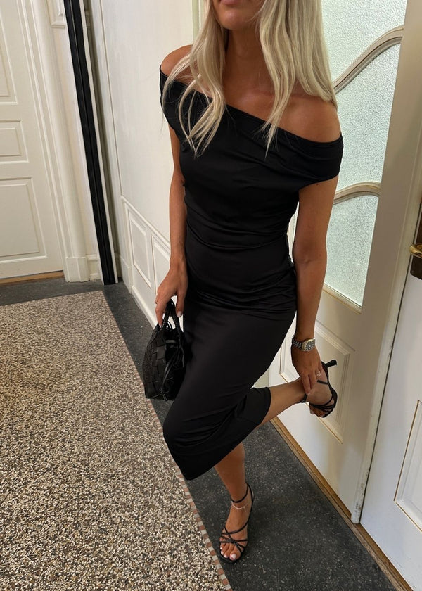 Long off-shoulder dress in elastic recycled material. Parissamd dress is fitted and has ruffle details at the sides. The model is 175 cm and wears a size S/36.