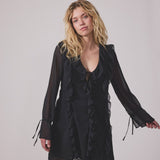 Short black dress with frill details and a loose fit. NorrisMD dress has a v-neck and long, wide sleeves with tiebands.