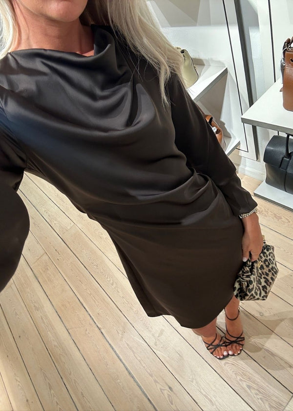 Our very popular and always sold out Tailormd dress now in a new shorter version with long sleeves. The dress is brown and has flattering gathering at the waist and a slight waterfall neckline. The TailorMD dress is made in a beautiful satin and has long sleeves and an invisible zipper in the back.
