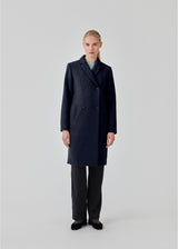Beautiful, knee-length wool coat in navy sky. Odelia coat is closed at front by 4 buttons and is fitted around the waist, which gives a feminine look. Because of the high content of wool the jacket will be perfect for fall and the mild winters.