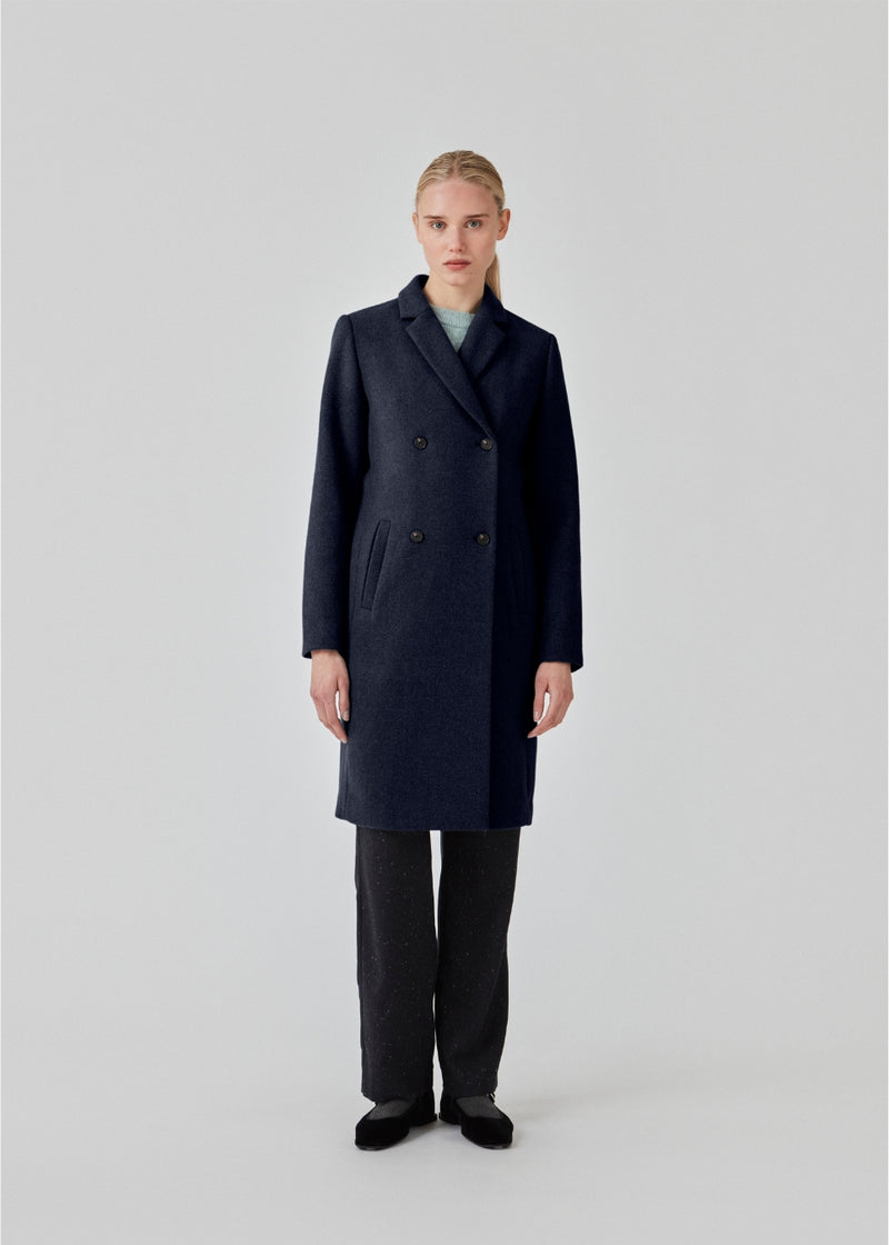 Beautiful, knee-length wool coat in navy sky. Odelia coat is closed at front by 4 buttons and is fitted around the waist, which gives a feminine look. Because of the high content of wool the jacket will be perfect for fall and the mild winters.