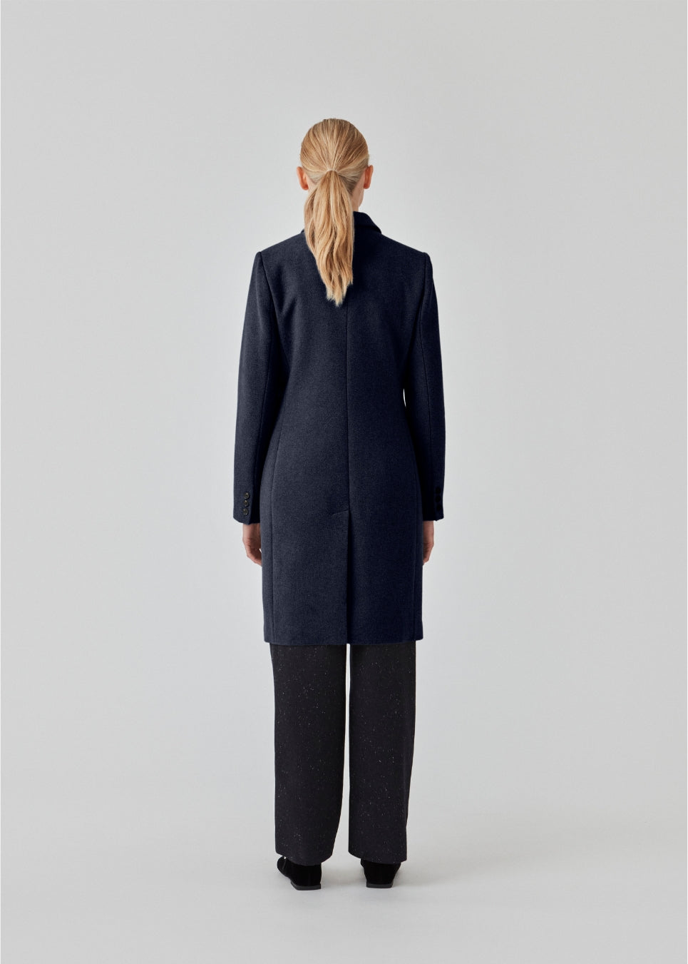 Beautiful, knee-length wool coat in navy sky. Odelia coat is closed at front by 4 buttons and is fitted around the waist, which gives a feminine look. Because of the high content of wool the jacket will be perfect for fall and the mild winters.