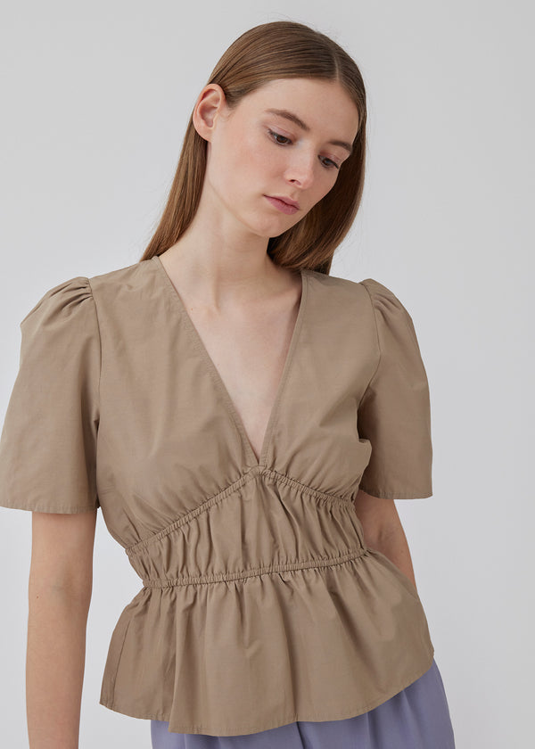 Beige top made from a cotton mix with short, slightly puffed, sleeves, and a deep v-neckline. DeenMD top has a flattering ruched detail below the chest and at the waist. The model is 177 cm and wears a size S/36.