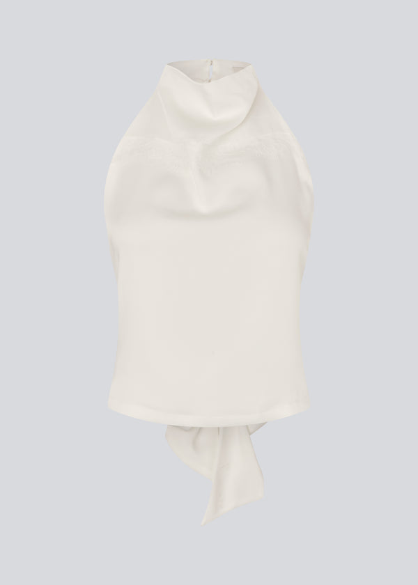 Halternecktop with a tiedetail in satin. Timmiemd top has an open back and a button closure at the neck. The model is 175 cm and wears a size s/36.