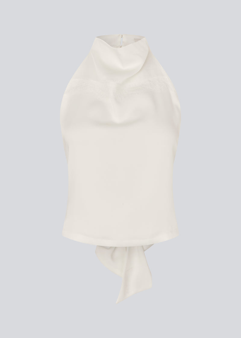 Halternecktop with a tiedetail in satin. Timmiemd top has an open back and a button closure at the neck. The model is 175 cm and wears a size s/36.