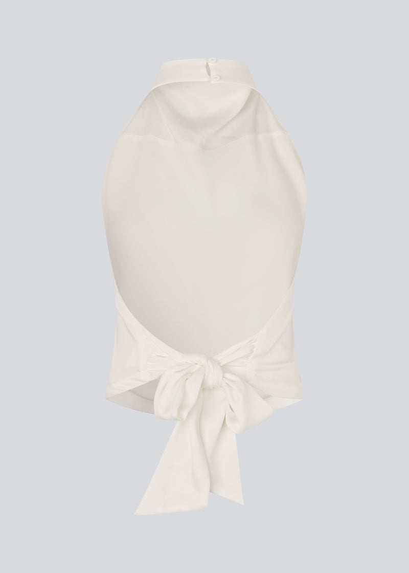 Halternecktop with a tiedetail in satin. Timmiemd top has an open back and a button closure at the neck. The model is 175 cm and wears a size s/36.