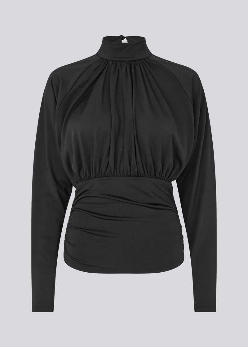 Elegant black blouse featuring a high neckline and long sleeves. Designed with delicate gathered details at the bust and waist to create a flattering silhouette. A subtle button closure at the back of the neck adds a refined and feminine touch. The stretchy fabric ensures a comfortable fit, while the draped design offers timeless elegance. Perfect for both everyday wear and special occasions.