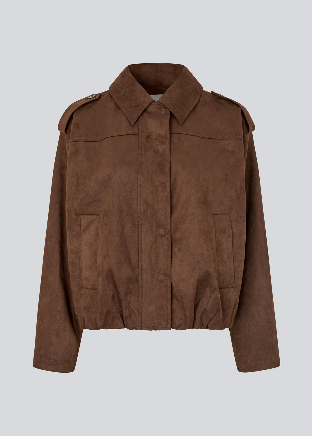 Short brown jacket made from a soft, suede-like material. Features a classic shirt collar, hidden zip and button closure at the front, and practical front pockets. The structured shoulders with strap details and the slightly elasticated hem add a modern, tailored touch. A versatile and stylish piece, perfect for transitional weather and everyday wear.