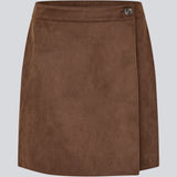 Short brown skirt in a suede-look fabric featuring an elegant wrap design. Closes with a decorative side button, adding a sleek and feminine touch. The soft material ensures a comfortable fit, while the minimalist cut makes it easy to style for both casual and more formal occasions. 