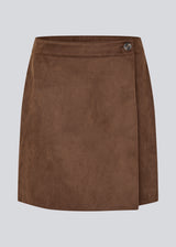 Short brown skirt in a suede-look fabric featuring an elegant wrap design. Closes with a decorative side button, adding a sleek and feminine touch. The soft material ensures a comfortable fit, while the minimalist cut makes it easy to style for both casual and more formal occasions. 