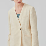 DimeMD blazer er designet i et tekstureret bomuldsmix med foer. Blazeren er uden krave og revers, men har en asymmetrisk wrap-detalje med en enkelt synlig knap. Modellen er 177 cm og har en størrelse S/36 på.  Style blazeren med matchende shorts: DimeMD shorts.