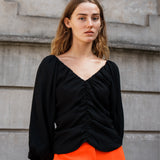 Long sleeved top in black in woven quality with long, voluminous sleeves. FisherMD top has a v-neckline in front and back with ruched seams, adding a drapy effect.