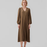 Long dress with long puff sleeves in a shiny satin with a pattern. CarmelMD dress is detailed by a deep v-neck and pleat for extra width in the skirt.  The model is 177 cm and wears a size S/36.