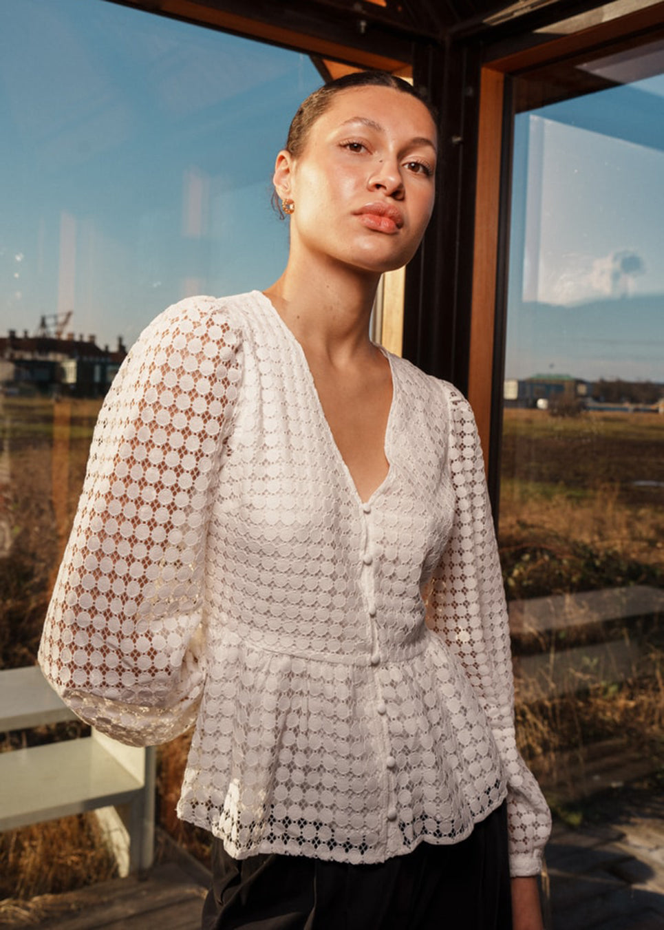 Top in white in a slightly transparent lace quality. HattieMD top has a v-neckline with button closure in front, long balloon sleeves, and a peplum-shaped waist. The model is 175 cm and wears a size S/36.