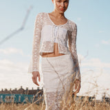 Fitted top in white stretchy lace with flared sleeves. TildeMD lace top has a deep V-neckline and two tiebands in the front.