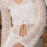 Fitted top in white stretchy lace with flared sleeves. TildeMD lace top has a deep V-neckline and two tiebands in the front.