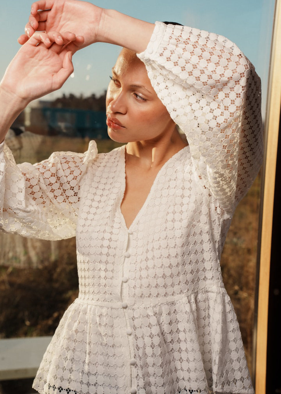 Top in white in a slightly transparent lace quality. HattieMD top has a v-neckline with button closure in front, long balloon sleeves, and a peplum-shaped waist. The model is 175 cm and wears a size S/36.